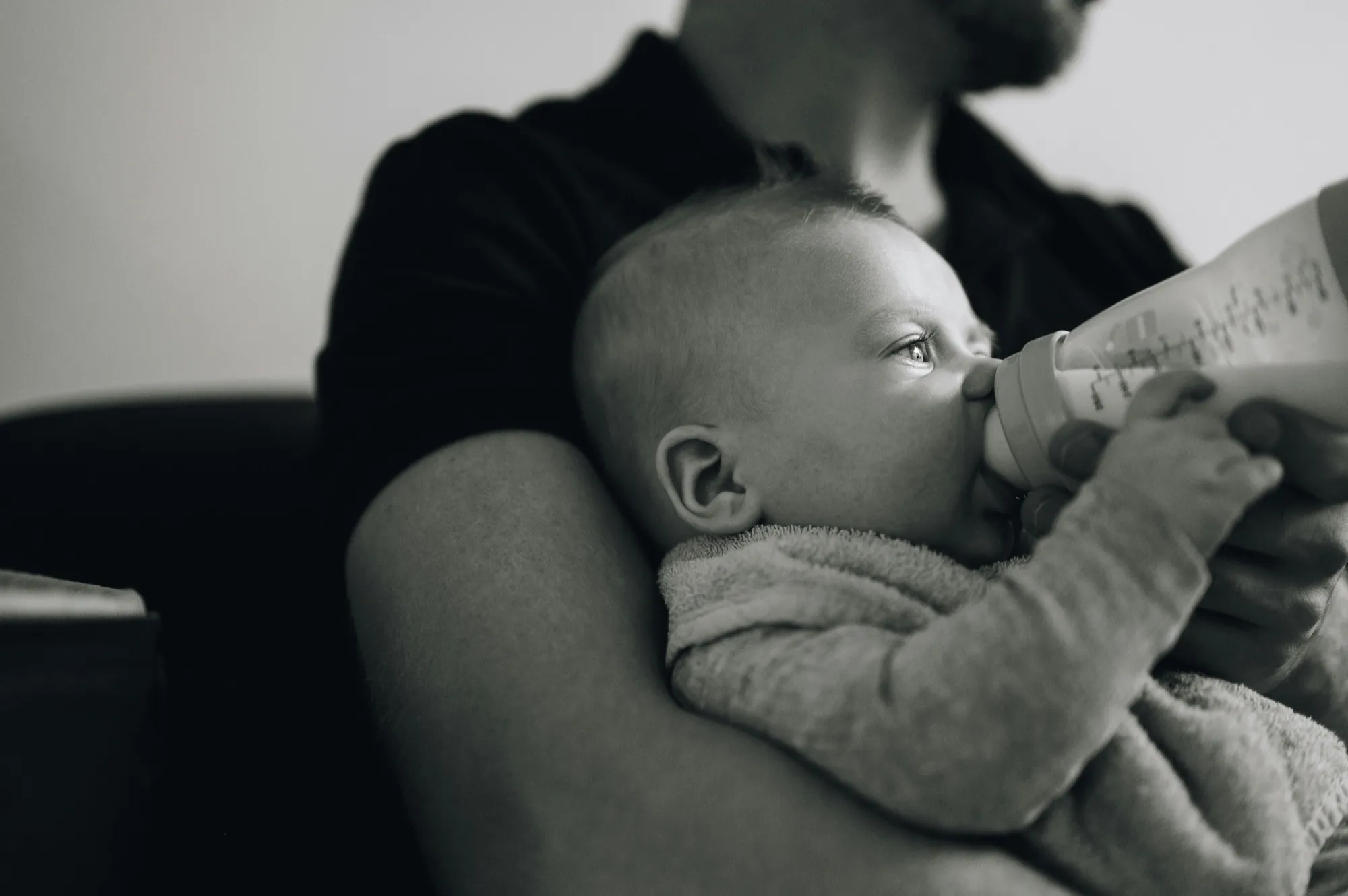 Dad holding his baby in one arm while giving a bottle